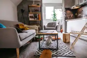 gettyimages-1179741843-e1715289141529-1 Small, quiet Fluffy Maltese dog sitting under the table at modern apartment.