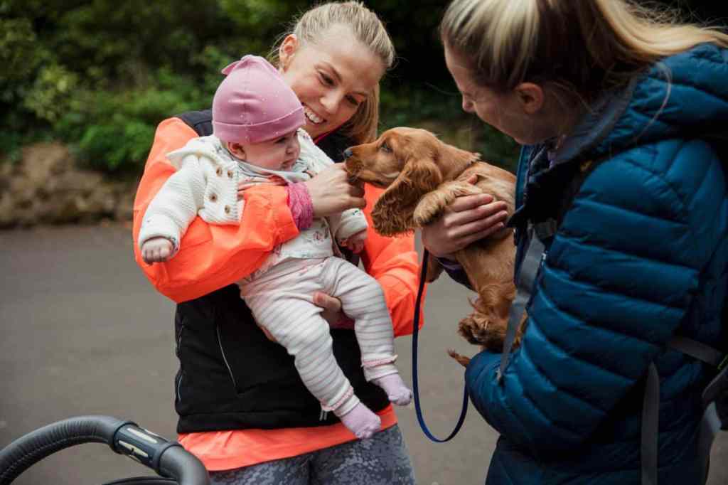 img_3172-e1729877417445 An adorable baby girl and Cocker Spaniel puppy have a friendly interaction with each other accompanied by their mothers in the park.